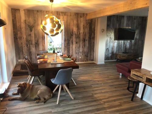 a dog laying on the floor next to a dining room table at Zu Fuß zum Strand - familienfreundlich zwischen Wismar und Boltenhagen Wallbox am Haus! in Beckerwitz