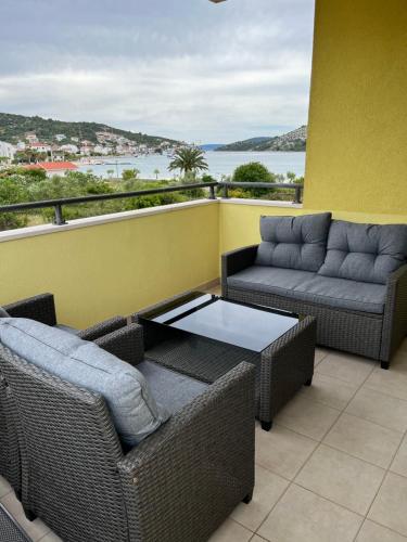 a balcony with two wicker chairs and a coffee table at Apartmani Marino in Vinišće