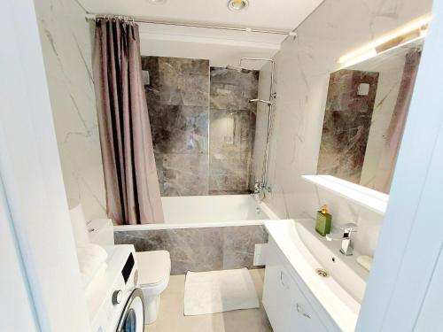 a white bathroom with a tub and a sink at Уютные апартаменты в новострое на Ботанике in Chişinău