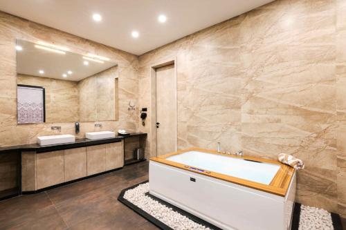 y baño con bañera y 2 lavabos. en Muhurat Hotel and Resort, en Māndhar