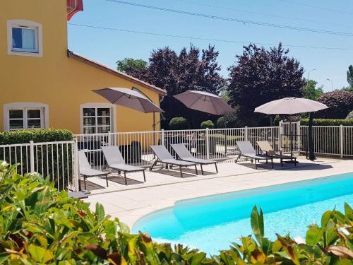 - une piscine avec des chaises et des parasols à côté d'une maison dans l'établissement ibis Manosque Cadarache, à Manosque