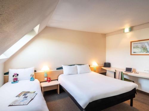 Habitación de hotel con 2 camas y escritorio en ibis Creil Sur Oise, en Villers-Saint-Paul