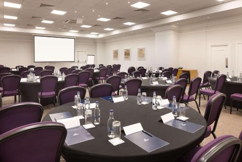 a conference room with tables and purple chairs and a screen at Hilton Nottingham Hotel in Nottingham