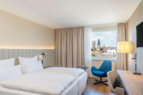 a hotel room with a bed and a desk and a window at NH Köln Altstadt in Cologne