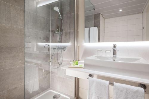 ein Bad mit einem Waschbecken und einer Dusche in der Unterkunft NH Köln Altstadt in Köln