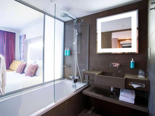 a bathroom with a sink and a shower with a mirror at Novotel Lyon Confluence in Lyon