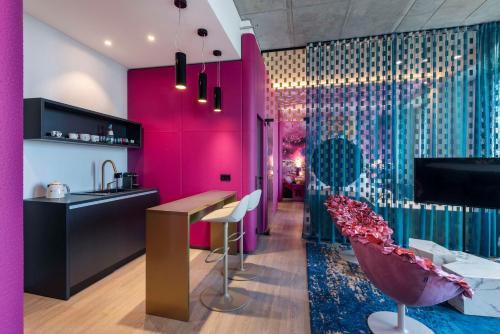 una cocina con paredes rosas y moradas y un bar en nhow Frankfurt en Frankfurt