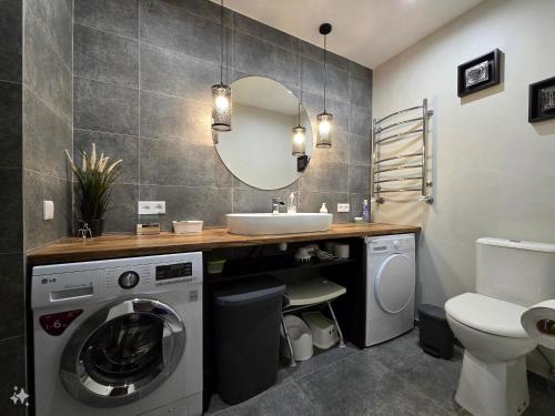 a bathroom with a sink and a washing machine at Guest House BENHAUS ar pirti un āra kublu in Sarkaņi