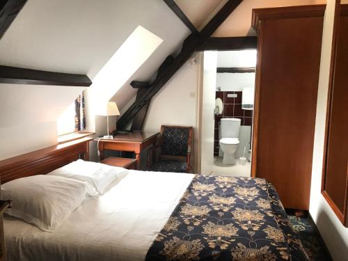 勒瓦斯特的住宿－Logis Hôtel & Restaurant - Le Château Des Tourelles，一间带一张床和一张书桌的卧室以及一间浴室。