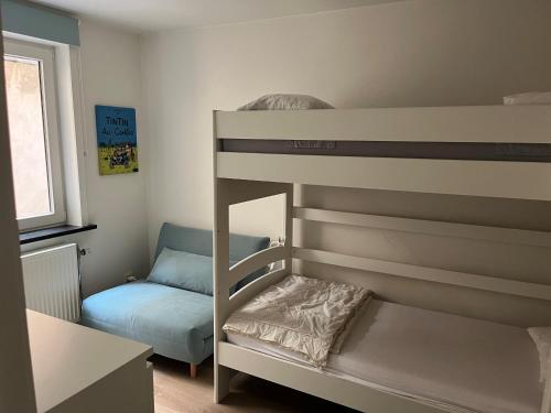 Etagenbett in einem Zimmer mit einem Bett und einem Sofa in der Unterkunft Tof en ruim appartement in Heist-Aan-Zee! in Knokke-Heist