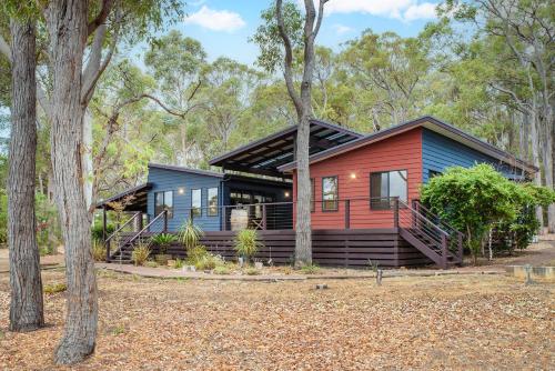 a home in the woods with a blue and red house at Cape Illawarra Holiday House Margaret River in Margaret River Town