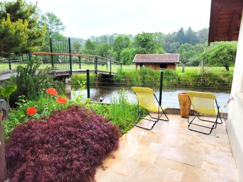 3 Stühle auf einer Terrasse mit einem Teich in der Unterkunft Château de Beauménil, paisible et familial in Beauménil