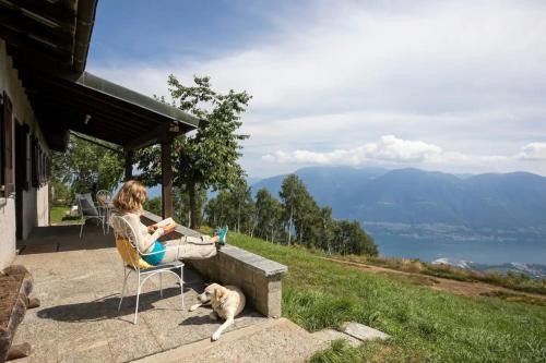 a woman sitting in a chair next to a dog at Oasi di pace vista lago-Cardada-Locarno in Orselina