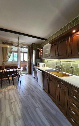 a kitchen with wooden cabinets and a dining room with a table at Spacious & cleаn 4 isolated rooms best for groups in Bratislava
