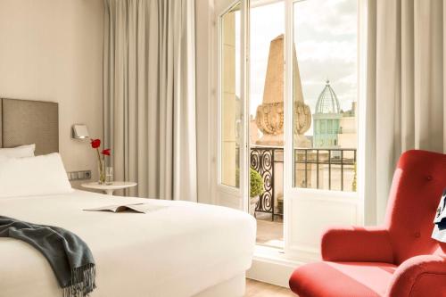 una camera d'albergo con un letto, una sedia e una finestra di NH Collection Brussels Centre a Bruxelles