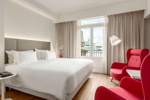a hotel room with a bed and a red chair at NH Collection Brussels Centre in Brussels