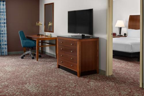 a hotel room with a television on a dresser with a bed at Hilton Garden Inn Milford in Milford