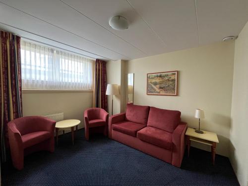 a hotel room with a red couch and two chairs at Boulevard Hotel Scheveningen in Scheveningen