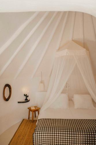 a white bedroom with a bed with a canopy at Les Bains Gardians in Saintes-Maries-de-la-Mer