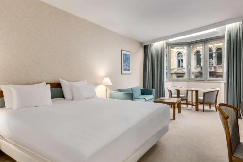 una habitación de hotel con una cama grande y una mesa en NH Gent Belfort en Ghent