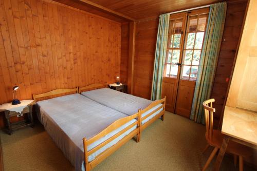 ein Schlafzimmer mit einem Bett in einem Holzzimmer in der Unterkunft Arnica 1 in Chateau-d'Oex