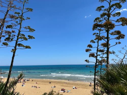 a beach with people on the sand and the ocean at Sunlands 50 meters from the sandy beach with wifi in Avola