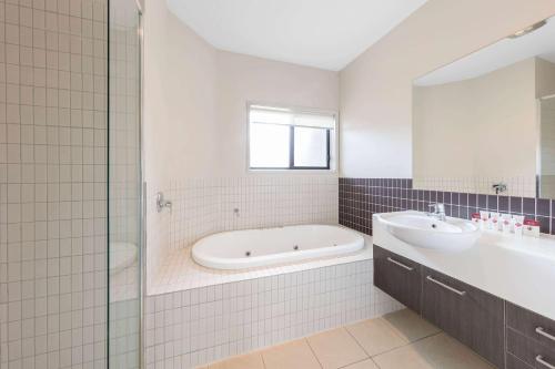 a white bathroom with a tub and a sink at Club Wyndham Seven Mile Beach, Trademark Collection by Wyndham in Cambridge
