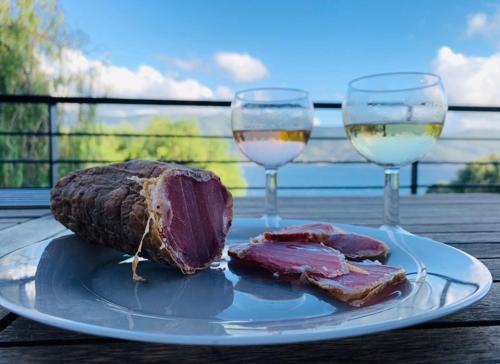 une assiette de viande et deux verres de vin sur une table dans l'établissement Les 2 anes, à Casaglione