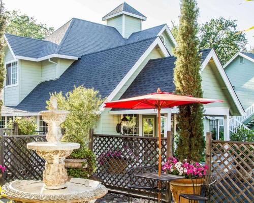 a house with a fountain and a red umbrella at The Inn at Baechtel Creek in Willits