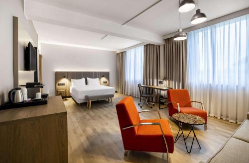 um quarto de hotel com uma cama e uma sala de estar em NH Luxembourg no Luxemburgo