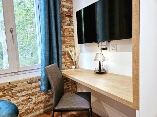 un bureau avec une télévision et une chaise dans une pièce dans l'établissement Luxine 2 - Appartement 4 pers - Proximité Gare Matabiau, à Toulouse