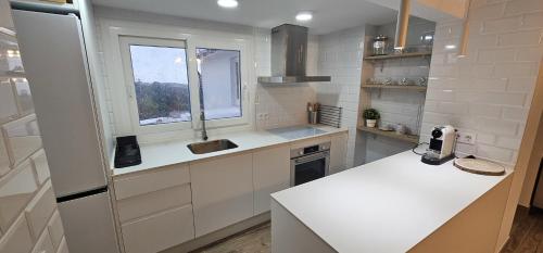 cocina blanca con encimera y ventana en Casa Plaza Alta, en Alcalá de los Gazules