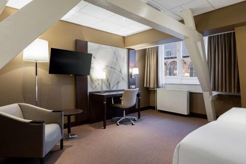 Habitación de hotel con cama, escritorio y TV. en NH Centre Utrecht Hotel, en Utrecht