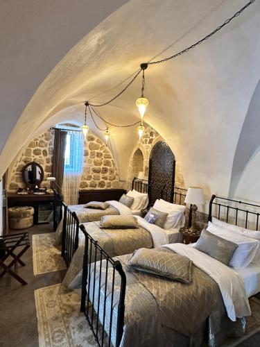 a bedroom with four beds in a room with a stone wall at Mardius Tarihi Konak in Mardin