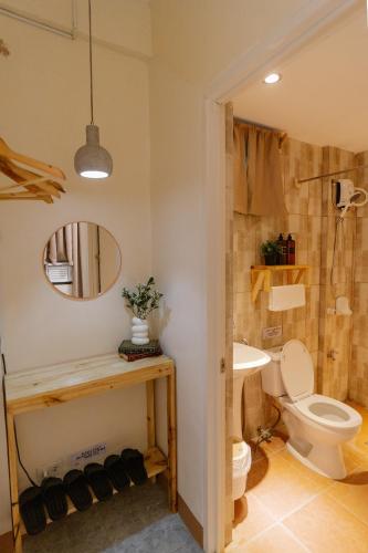 a bathroom with a toilet and a sink and a mirror at Pallet Homes - Petalsville in Iloilo City