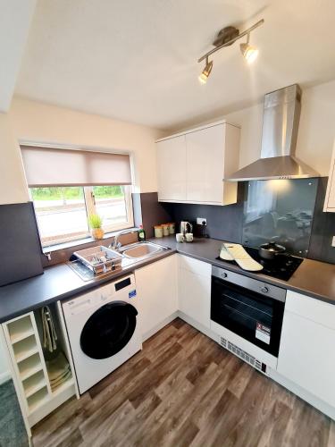 a kitchen with white cabinets and a sink and a stove at Modern 2 bedroom apartment in Historical Spa town in Droitwich