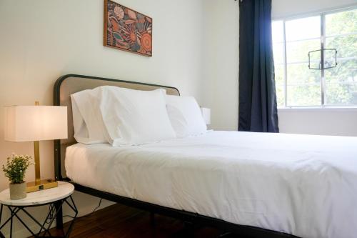 a bedroom with a bed with white sheets and a window at Los Angeles Miracle Mile Spacious 2BR Townhouse in Los Angeles