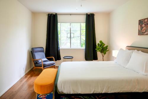 a bedroom with a bed and a chair and a window at Los Angeles Miracle Mile Spacious 2BR Townhouse in Los Angeles