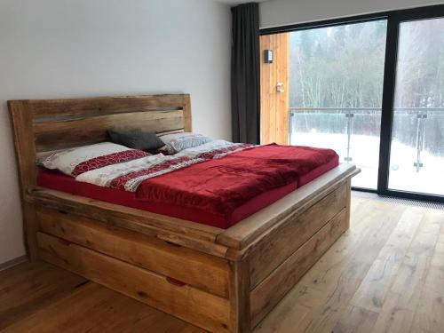 a wooden bed in a room with a large window at Hotel U Kabinky in Janske Lazne