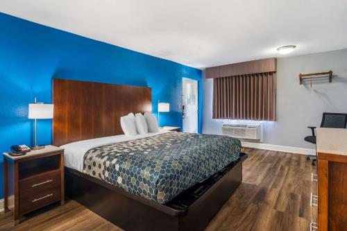 a bedroom with a bed with a blue wall at Econo Lodge Inn & Suites Virginia Beach - Norfolk in Virginia Beach