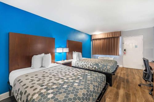a hotel room with two beds and a blue wall at Econo Lodge Inn & Suites Virginia Beach - Norfolk in Virginia Beach