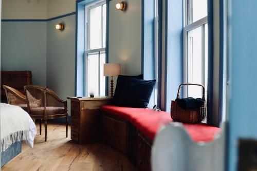a room with a bed with a red bench and windows at The London & Paris Hotel in Folkestone