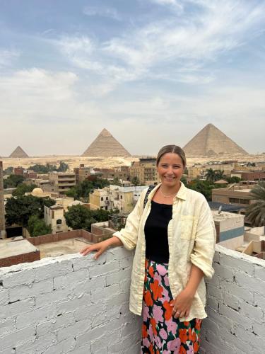 uma mulher de pé numa parede em frente às pirâmides em LOAY PYRAMIDS VIEW no Cairo