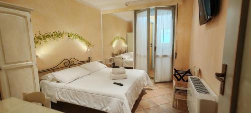 1 dormitorio con 1 cama blanca y 1 habitación con espejo en Elisart Guest House, en Alghero