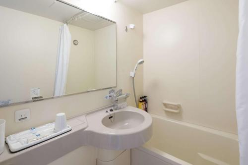 Baño blanco con lavabo y espejo en Comfort Hotel Saga, en Saga