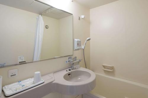 Comfort Hotel Yamagata في ياماغاتا: حمام أبيض مع حوض ومرآة
