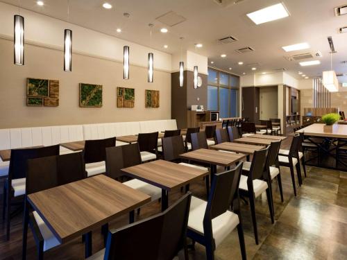 Comfort Hotel Yamagata في ياماغاتا: غرفة طعام مع طاولات وكراسي خشبية