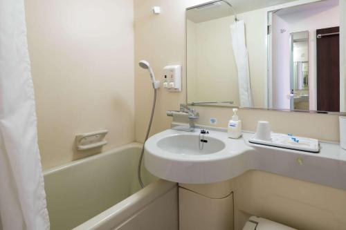 a bathroom with a sink and a bath tub with a mirror at Comfort Hotel Hakodate in Hakodate