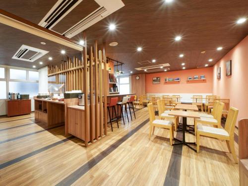 a restaurant with tables and chairs and a bar at Comfort Hotel Kumamoto Shinshigai in Kumamoto