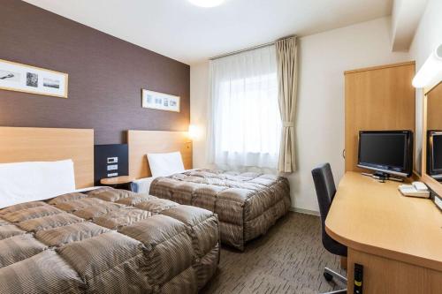 a hotel room with two beds and a desk at Comfort Hotel Kitami in Kitami